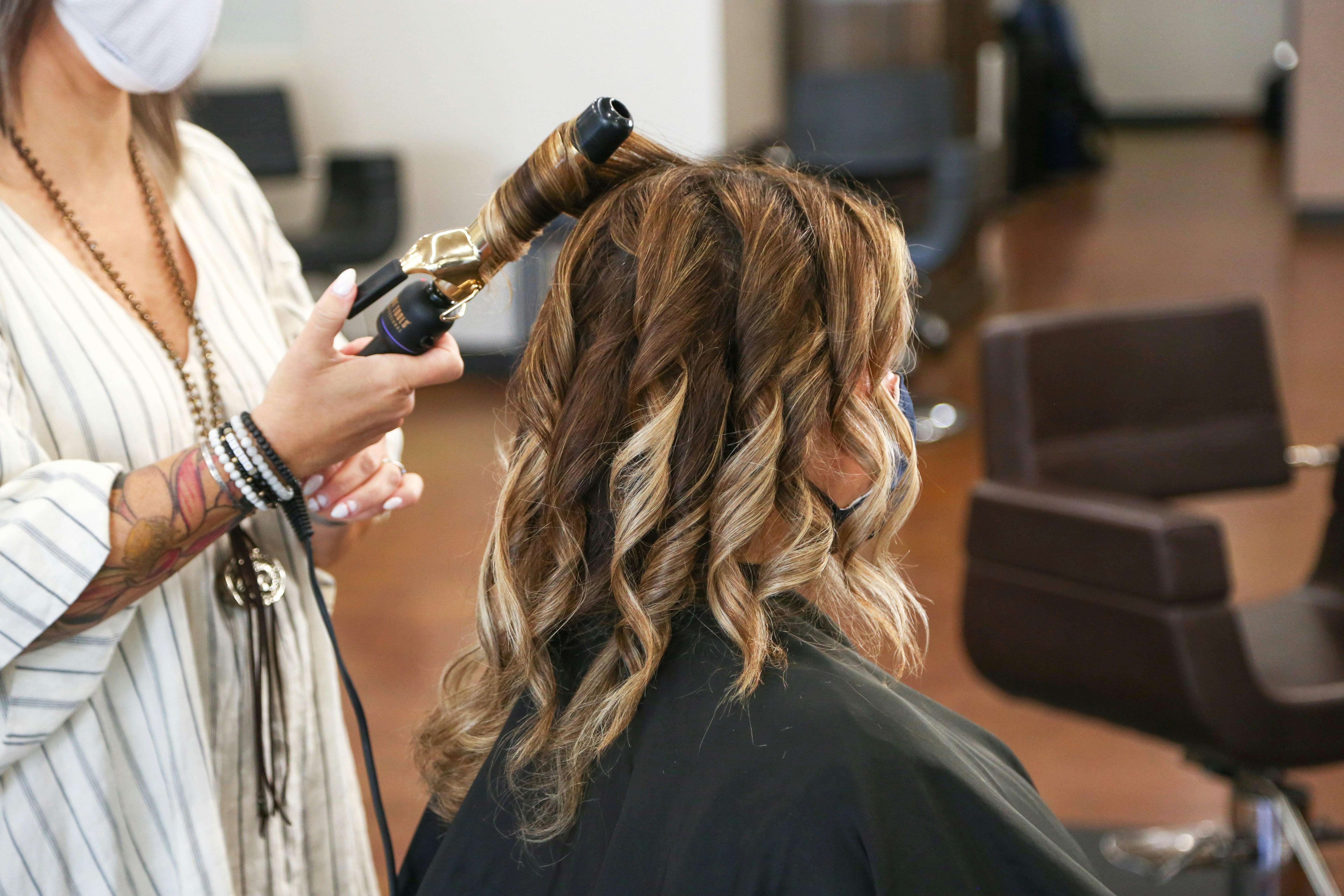 Stylist curling client's hair at Mira & Co.